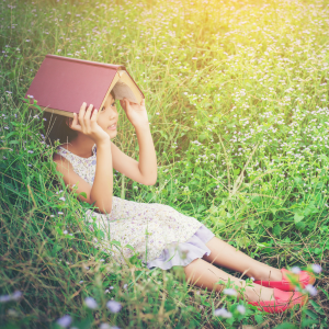 Petite fille dans un jardin avec un livre