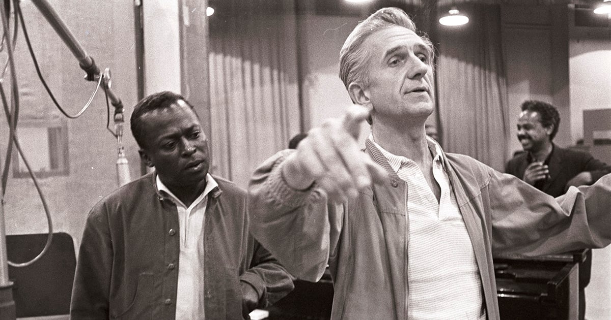 Photo en noir et blanc des deux artiste Gil devant Miles dirigeant les musiciens