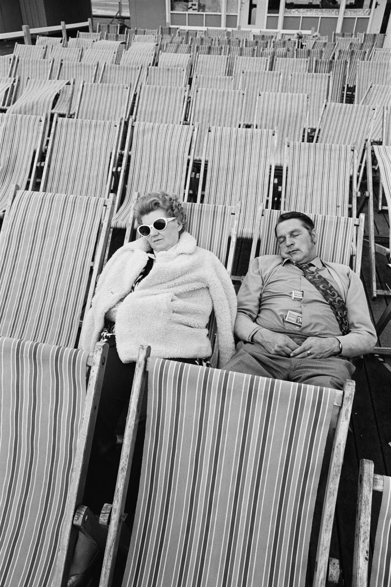 Photographie en noir et blanc, deux personnes endormies en bord de mer