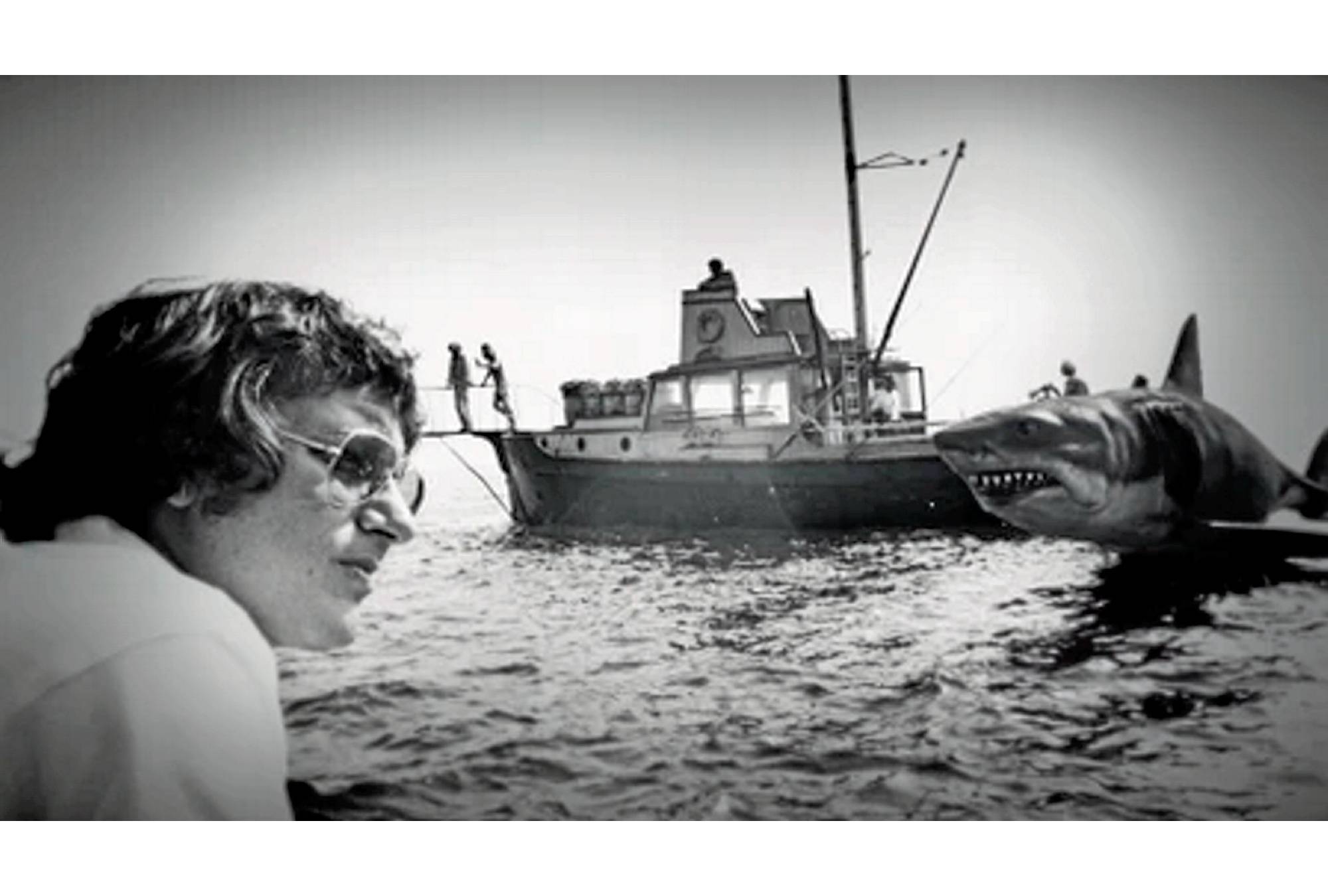 Photo en noir et blanc de Steven Spielberg en tournage avec un requin mécanique