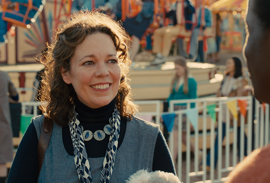 Une femme souriant à un homme de dos, scène dans une fête foraine.