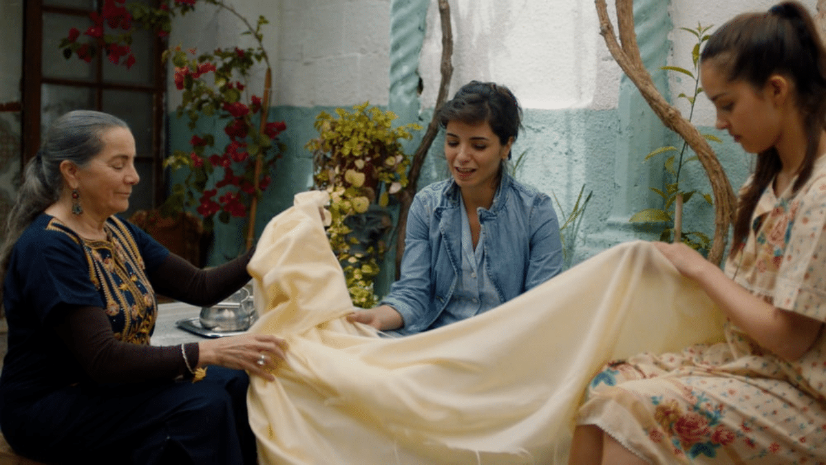 Trois femmes touchent un morceau de tissu en extérieur