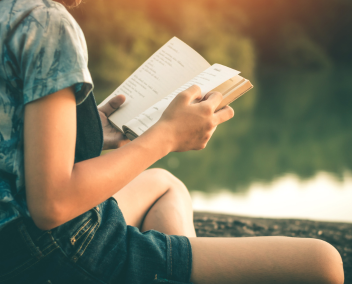 Une jeune femme en train de lire au bord d'un lac